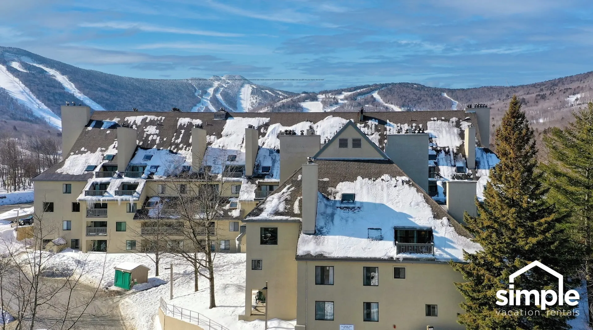 Aerial drone view of Mountain Green Resort condominium buildings with Killington ski slopes and mountain vista in background, showing slopeside vacation rental location in Vermont